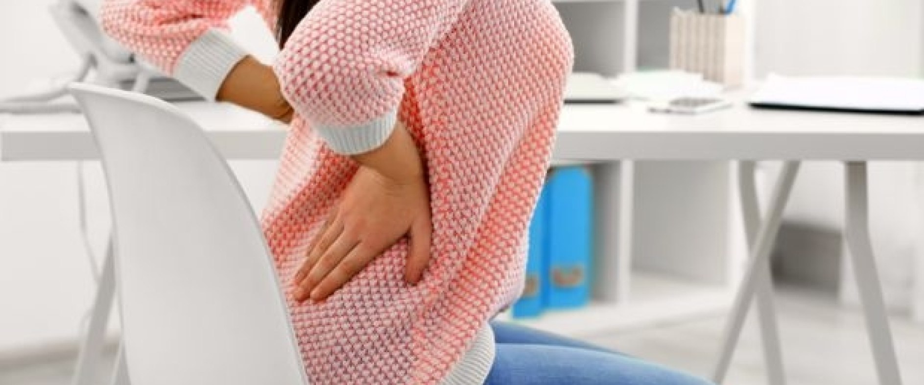 Mit Rückenschmerzen hat jeder im Laufe seines Lebens zu tun. Sie können durch Fehlstellungen zwischen Schädel und Unterkiefer entstehen Frau greift an Rücken