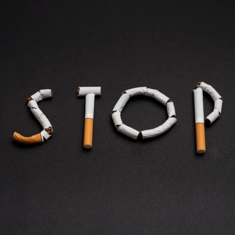 Aus Zigaretten wurde das Wort Stopp auf schwarzen Hintergrund gelegt